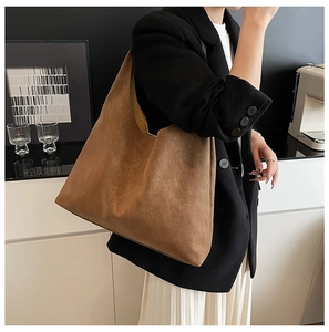 Close-up of a large brown matte suede tote bag styled in a modern minimalist setting