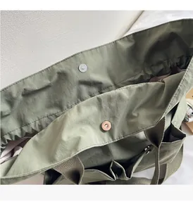 Detail of army green bucket bag showing metal magnetic closure and textured nylon fabric