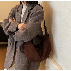 Detail of dark brown suede hobo bag shown with a stylish tweed blazer and adjustable strap
