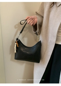 Detail of black hobo bag with vintage wooden beaded pendant and metal buckle handle