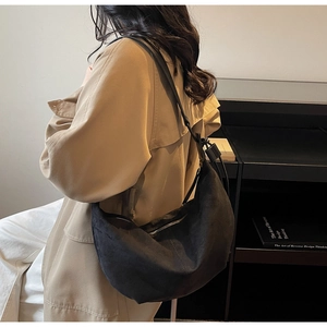 Close-up of minimalist black suede hobo bag with silver zipper and adjustable strap
