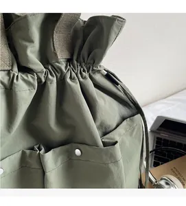 Detail of sage green nylon bucket bag with drawstring closure and multiple utility pockets