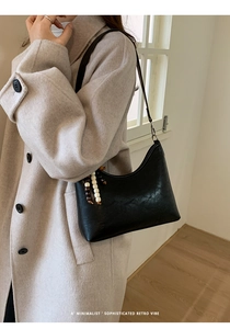 Chic black bucket bag with colorful bead charm paired with a minimalist beige wool coat