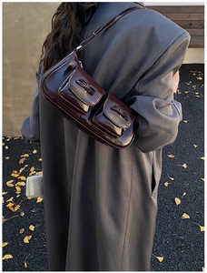 Deep burgundy glossy shoulder bag with dual bow pockets worn on a charcoal wool coat