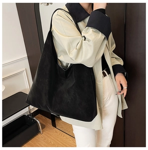 Detail of minimalist black matte suede shoulder bag shown on model for daily commuting