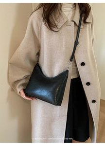 Minimalist black crescent bucket bag with leather strap shown in a retro style