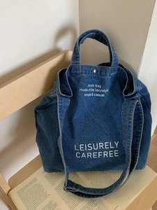 Grand sac cabas en denim bleu foncé vintage avec texte blanc sur une chaise en bois