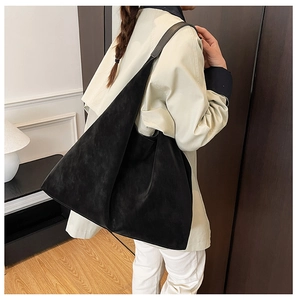 Macro shot of minimalist black tote bag side profile showing smooth drape and wide strap