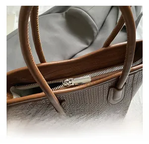 Detail showing silver metal zipper and woven texture on brown bucket bag