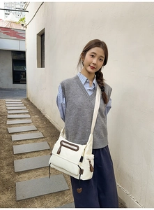 Detail view of a beige multi-pocket messenger bag on model in outdoor casual setting