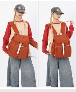 Detail view of brick red large capacity backpack with white contrast straps and pockets
