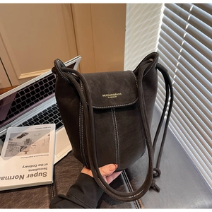 Détail du sac seau en suède avec surpiqûres blanches contrastées et logo doré chic