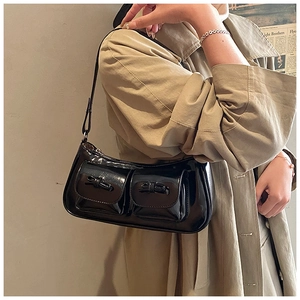 Detail of a black patent leather shoulder bag with bow accents and double pockets