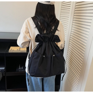 Close-up of black drawstring backpack featuring dual front pockets and metallic buckles