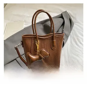 Detail of a brown PU leather bucket bag featuring woven texture and a cute puppy charm