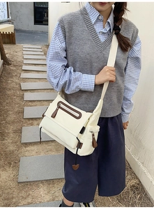 Detailed view of cream utility messenger bag with multiple functional pockets and brown zippers