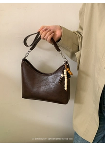 Detail of dark brown leather retro bucket bag with silver buckle and beaded charm