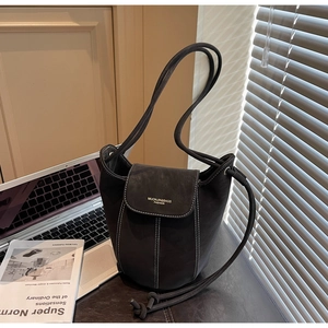 Détail du sac seau en daim gris avec coutures blanches contrastées et logo doré chic