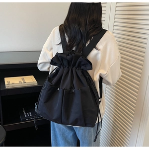 Close-up of black drawstring bucket bag showing polished synthetic fabric and ruffle detail