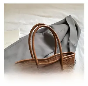 Detail of brown woven bucket bag featuring smooth leather handles and gold chain accents