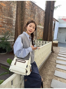 Outdoor shot of a beige canvas messenger bag with pockets and adjustable strap for casual style