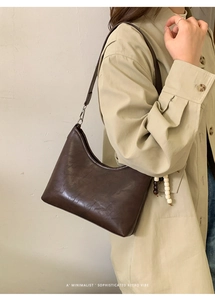 Close-up of a dark brown minimalist retro bucket bag featuring textured synthetic leather
