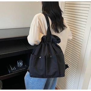 Detail showing high-capacity black drawstring nylon backpack with silver snap buttons