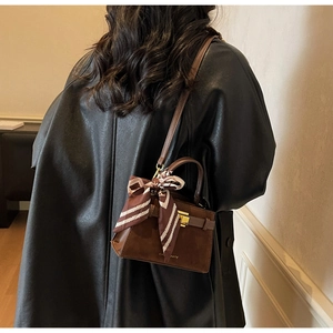 Detailed shot of brown Kelly handbag with silk scarf handle and gold hardware detail