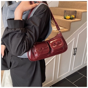 Detail view of burgundy leather shoulder bag with vintage bows and double front pockets