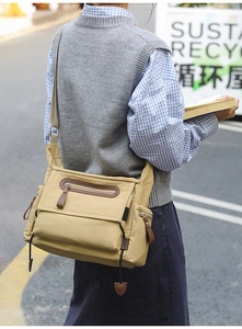 Detail view showing multi-pocket structure and khaki canvas material of messenger bag