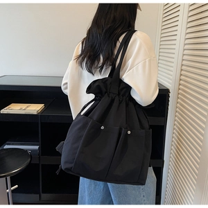 Detail of black nylon drawstring bucket bag with silver studs and multiple utility pockets