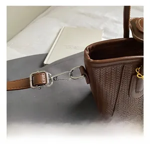 Detail of silver metal hook and adjustable brown woven leather strap on shoulder bag