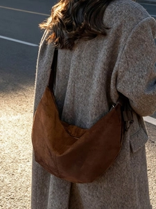 Brown faux suede crescent hobo bag for women with large capacity on a street background