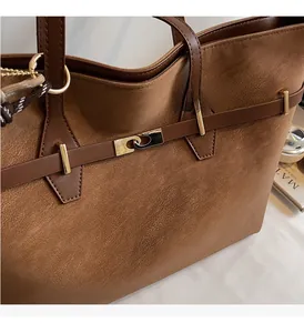 Detailed macro view of the brown leather tote bag with elegant golden metal buckle closure