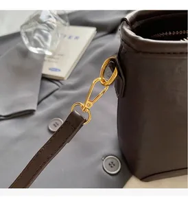 Close-up of premium gold hardware and brown leather stitching on a bucket bag