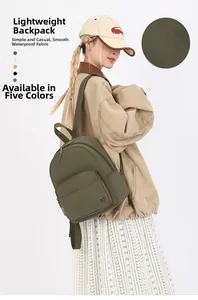 Detail view of military green waterproof nylon backpack worn by a model in casual style