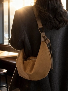 Brown faux suede crescent hobo bag shown on a model in warm indoor natural lighting