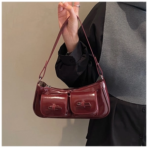 Detail of burgundy patent leather shoulder bag with two small bow pockets