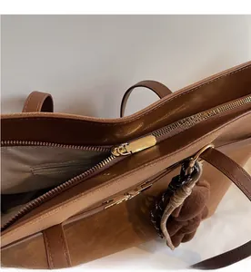 Detailed close-up of smooth metal zipper and herringbone fabric lining on brown tote bag
