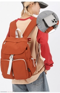 Detail of a brick red nylon backpack featuring multi-pockets and anti-theft back zip pocket