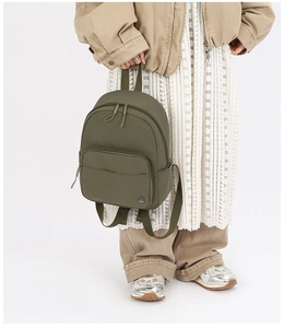 Detailed shot of an olive green nylon mini backpack featuring a circular metal logo