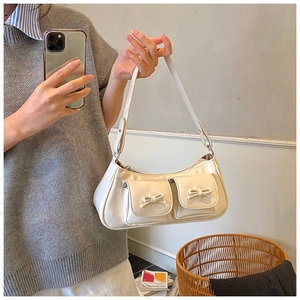 Detail of cream white leather shoulder bag with bow-decorated pockets and retro design