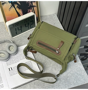 Macro detail of the dark green messenger bag featuring reinforced leather trim and zippers