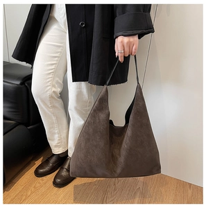 Detail shot of the large coffee brown matte tote bag carried by a model for size