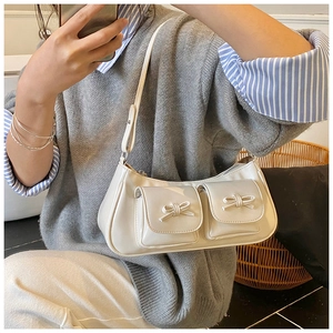 Detail of cream white faux leather shoulder bag with chic bow accents and dual pockets