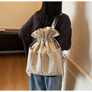 Detail view of beige canvas bucket bag with drawstring closure and outer pockets