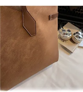 Close-up of brown tote bag showing reinforced handles and textured leather surface