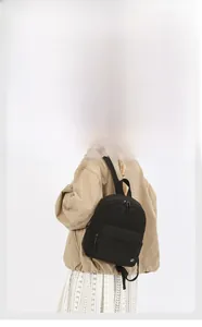 Detailed view of black nylon backpack with double zippers and brand logo patch