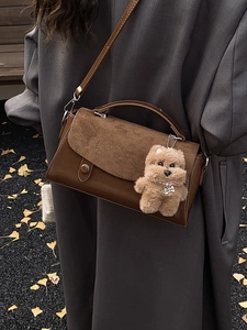 Braune Lederhandtasche mit Plüschhund-Anhänger getragen im herbstlichen Freien