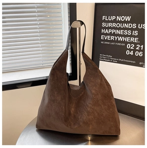 Detail of dark brown matte suede tote bag hanging on a minimalist metal display stand